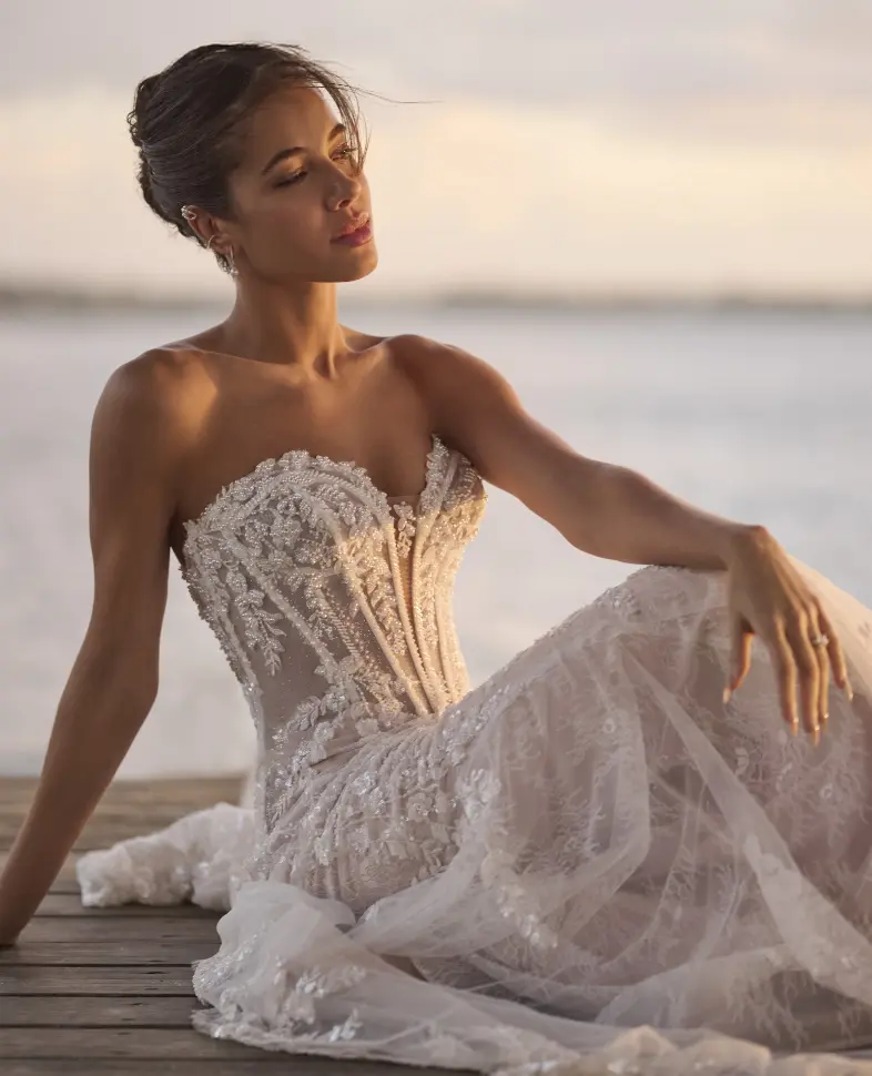 Model Sitting On A Boadwalk By The Ocean Wearing Lace Wedding Dress Called Benjie Royale By Maggie Sottero