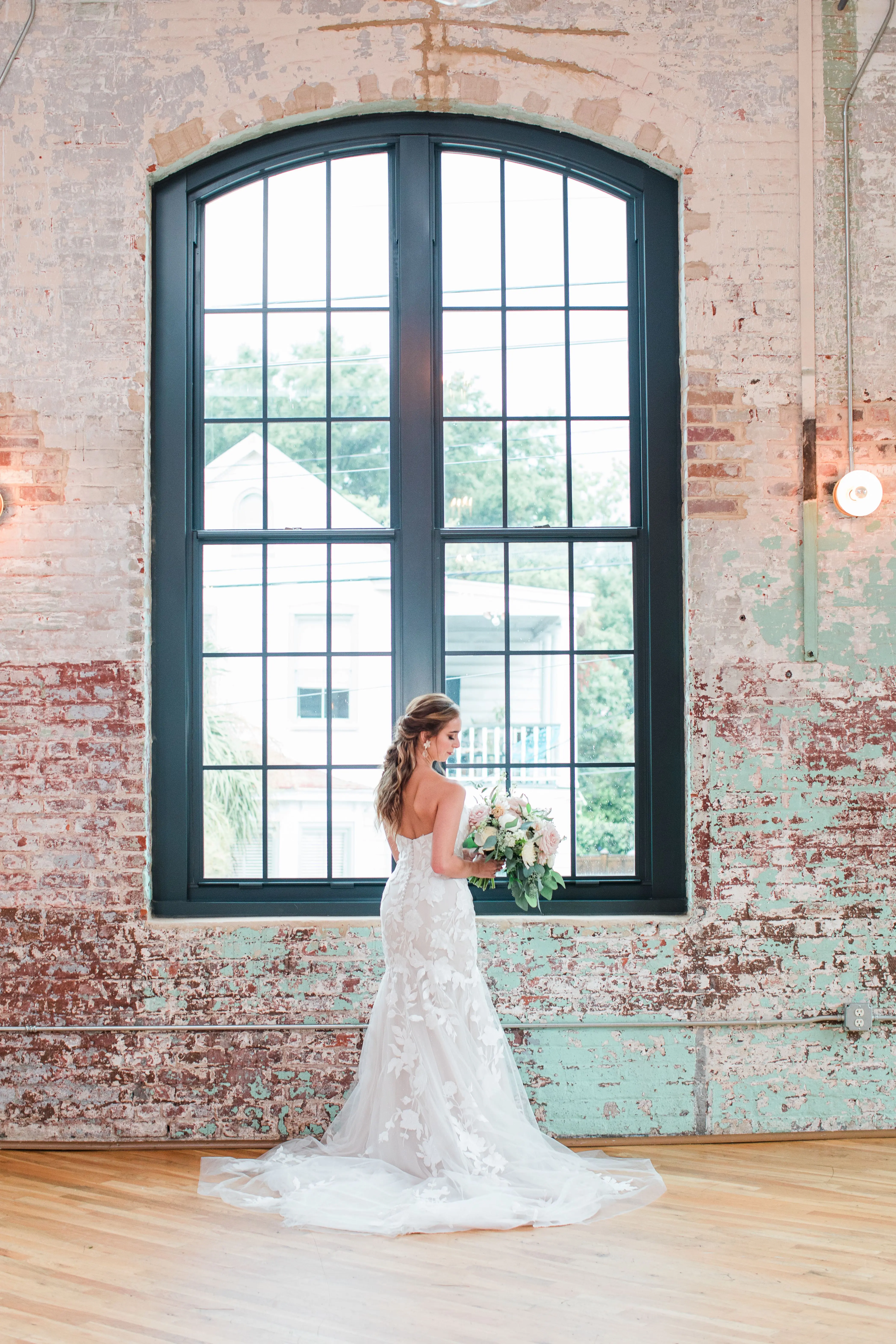 Bride wearing strapless mermaid wedding dress with oversized lace