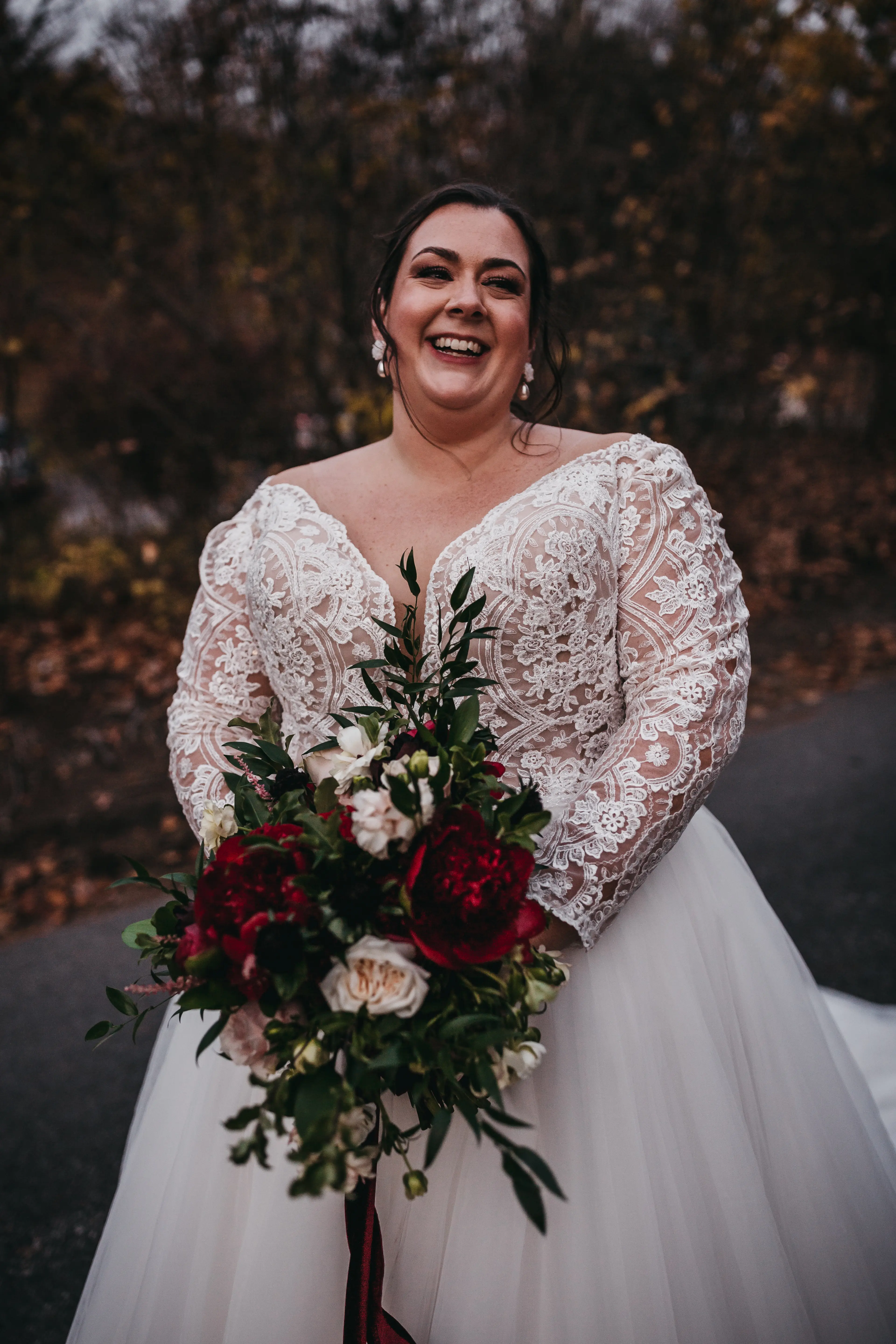 Plus Size Bride In Lace Long Sleeve Wedding Dress Called Mallory Dawn By Maggie Sottero Holding Red Bouquet